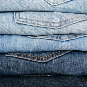 Closeup of stack of blue denim pants neatly arranged according to color from lightest to darkest
