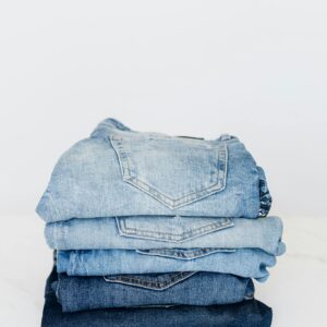 Pile of denim pants of different shades of blue placed on white shelf